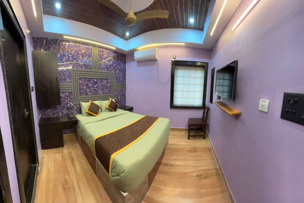A modern bedroom with a bed, nightstands, a TV, and a ceiling fan.