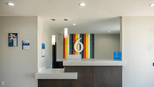 Una reception con una parete colorata a righe, un grande cartello con il numero '6' e un cartello informativo blu.