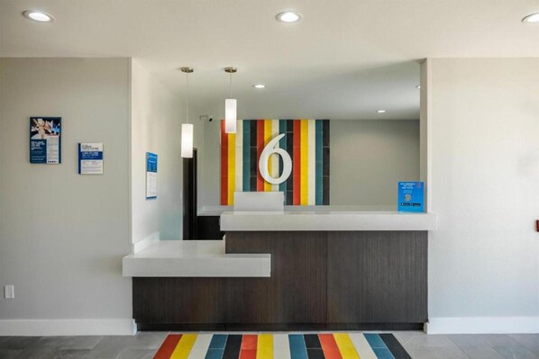 A reception desk with a colorful striped wall, a large number '6' sign, and a blue informational sign.
