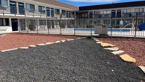 A building with a pool, a fenced courtyard, and a gravel path. - 1 Queen Bed|Nsmk,Kitchen (Grants)