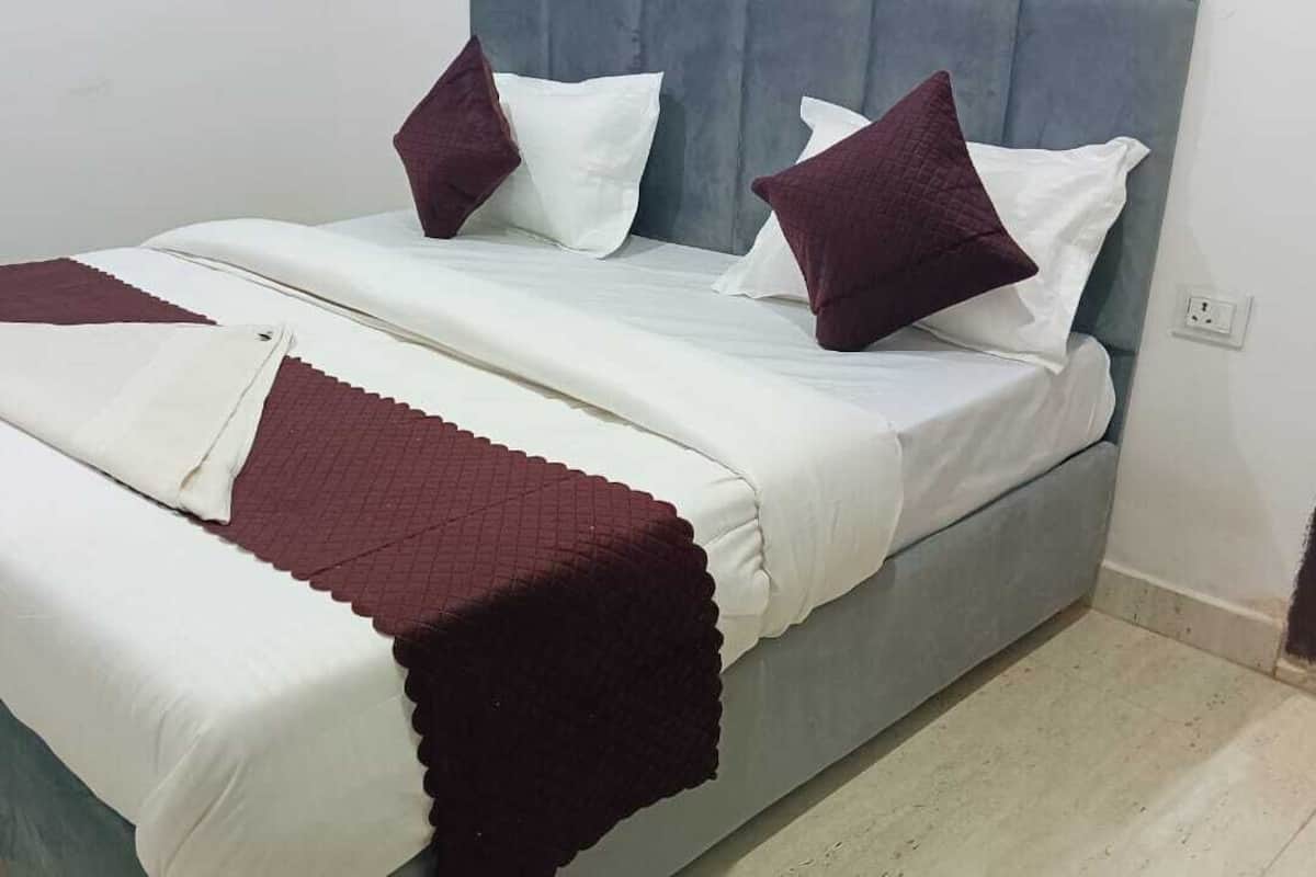A bed with a white mattress, a dark red blanket, and two pillows.