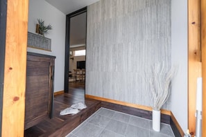 A hallway with a wooden floor, a grey tiled area, and a white vase with branches. - Miyako Island Breeze (Miyakojima City)