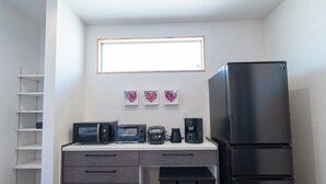 Eine kleine Küche mit Kühlschrank, Mikrowelle, Toaster und Kaffeemaschine.