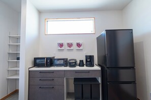Eine kleine Küche mit Kühlschrank, Mikrowelle, Toaster und Kaffeemaschine.