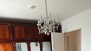 Ein Schlafzimmer mit einem großen Bett, einem Holzschrank, einer Chandelier und einem Spiegel.