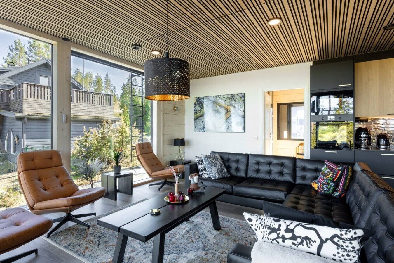 Un salon moderne avec un canapé, des fauteuils, une table basse et une grande fenêtre.