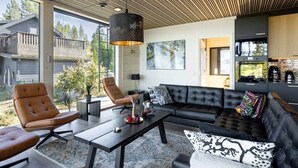 Ett modernt vardagsrum med en soffa, fåtöljer, ett soffbord och ett stort fönster.