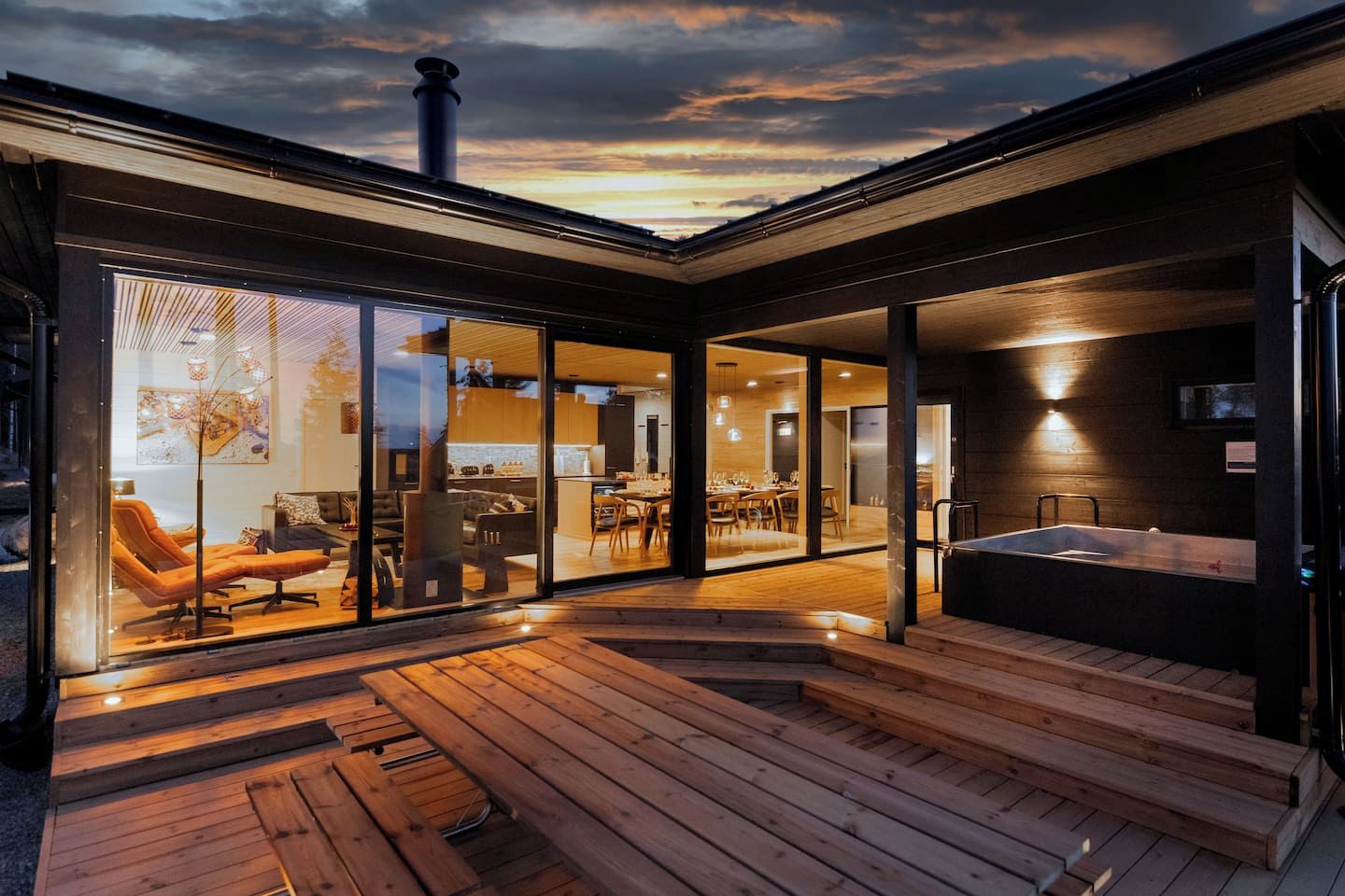 A modern house with a wooden deck, a dining area, and a hot tub.