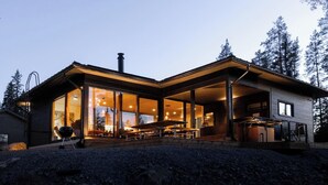 Ett modernt hus med stora glasfönster, en täckt uteplats och en skorsten.