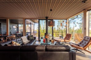 Un salon moderne avec un grand canapé en cuir noir, un plafond en bois et une cheminée.