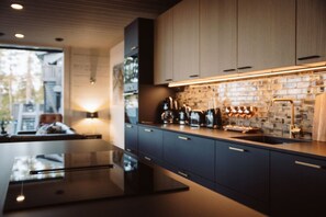 A modern kitchen with dark cabinetry, a central island, and a brick backsplash.