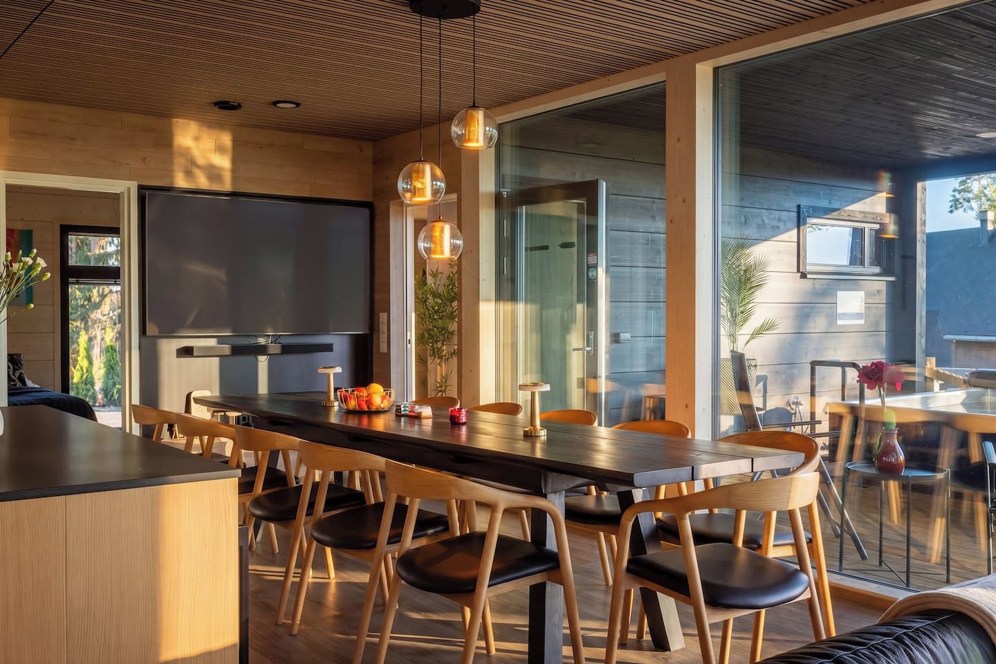 Una cocina moderna con una isla grande, sillas de madera e iluminación colgante.