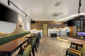 A restaurant interior with booths, tables, a stage, and a wall-mounted screen. - 3A Hometel Hanoi (Ha Noi)