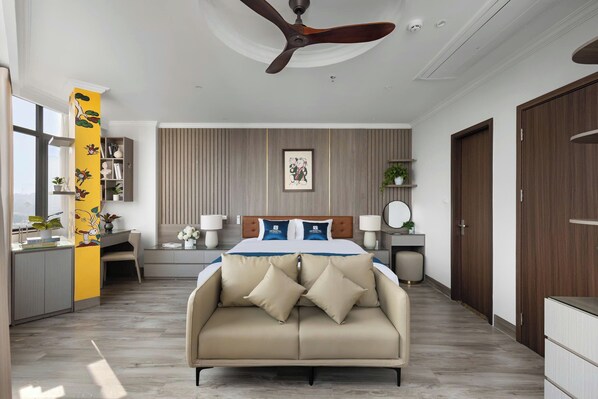 Un dormitorio moderno con cama, ventilador de techo, escritorio y vista a la ciudad.