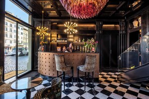 A bar area with a checkered floor, two leopard print chairs, a bar counter with bottles, and a decorative chandelier. - Argentum Boutique Hotel & SPA (Rome)