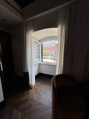Una habitación con un amplio ventanal, piso de parqué tipo espiga y vistas a edificios.