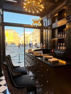 A bar with a view of the street, a counter with plates and glasses, and a selection of bottles on shelves. - Argentum Boutique Hotel & SPA (Rome)
