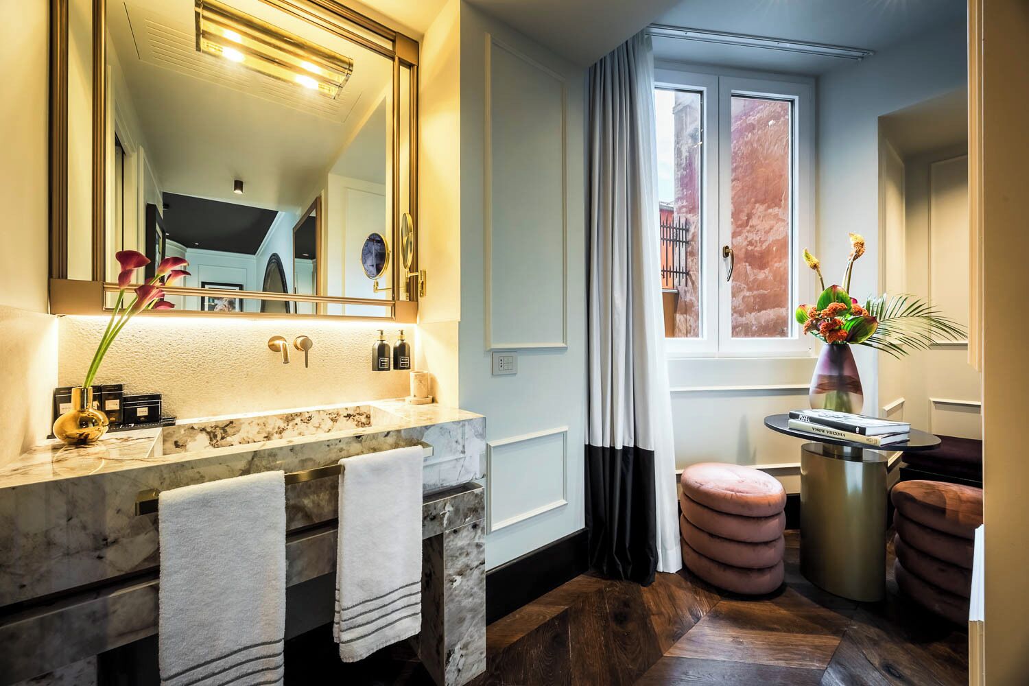 A modern bathroom with a marble sink, large mirror, and a window with curtains.