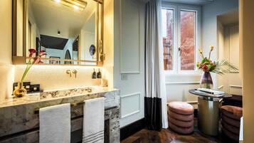 A modern bathroom with a marble sink, large mirror, and a window with curtains.