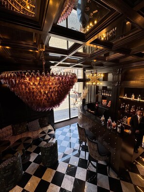 A bar area with a checkered floor, a chandelier, and a bar counter with bottles. - Argentum Boutique Hotel & SPA (Rome)