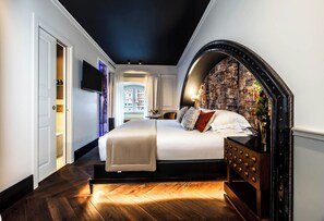 A bedroom with a large bed, a TV, and a view of buildings through a window. - Argentum Boutique Hotel & SPA (Rome)