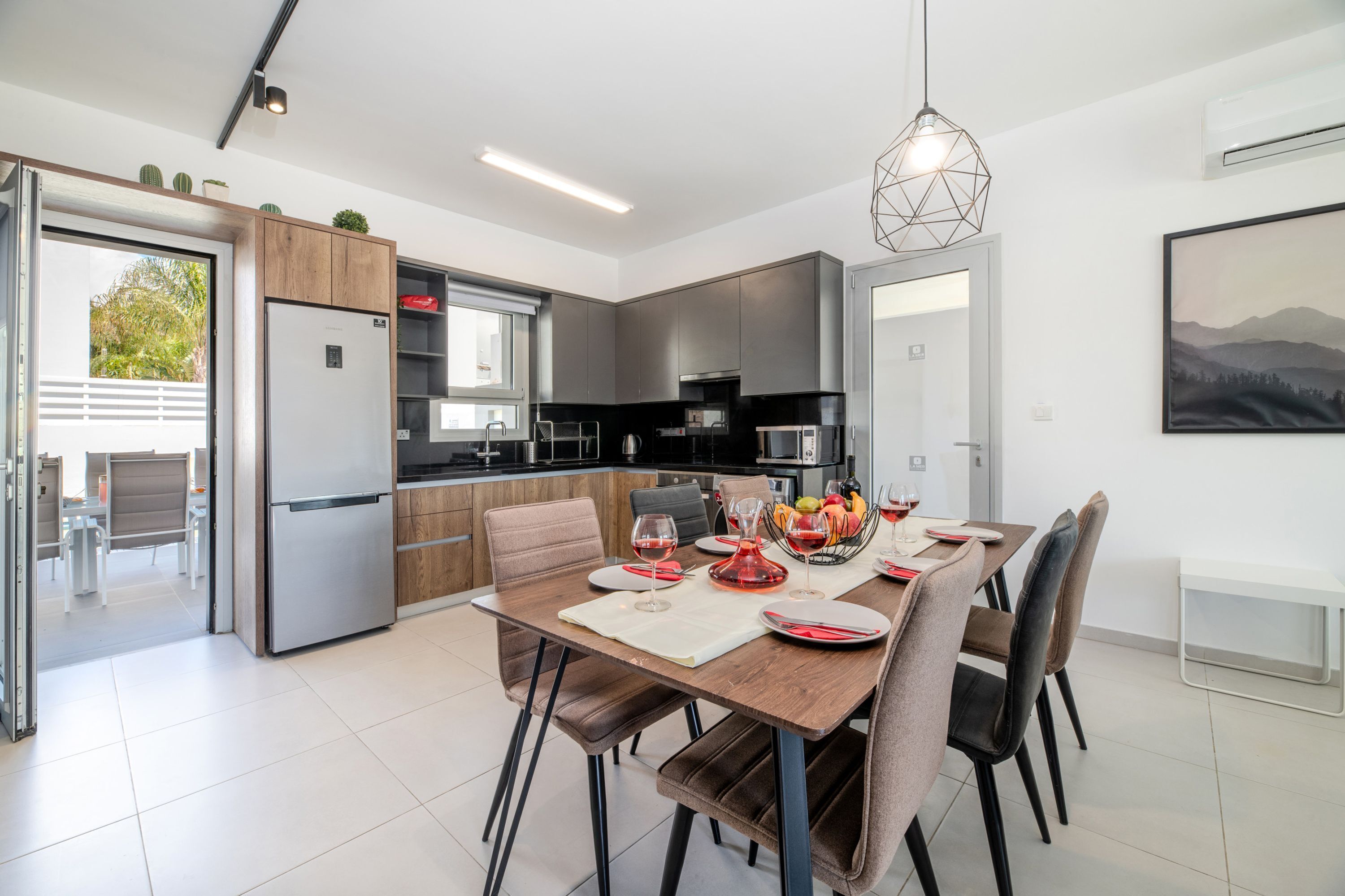 Cocina moderna con comedor, que incluye un refrigerador, microondas y mesa de comedor con platos y vasos.