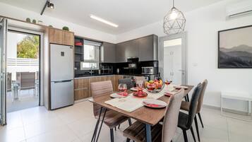Cocina moderna con comedor, que incluye un refrigerador, microondas y mesa de comedor con platos y vasos.