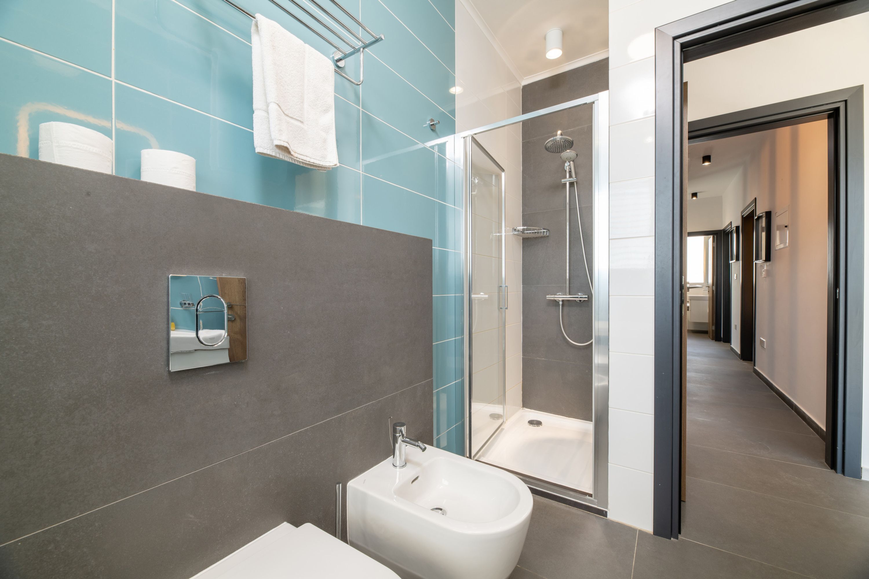 A modern bathroom with a glass shower enclosure, a bidet, and a mirror.