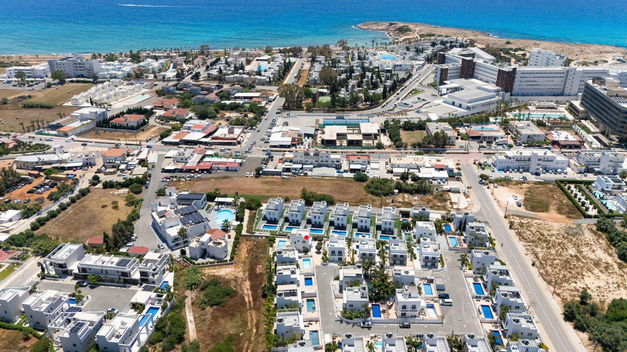 An aerial view of a coastal resort area with multiple buildings, roads, and a beach.