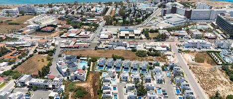 An aerial view of a coastal resort area with multiple buildings, roads, and a beach.