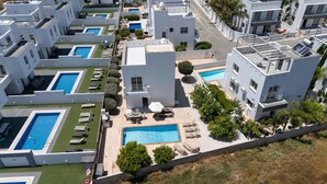 A modern residential complex with multiple swimming pools, outdoor seating areas, and a central pool. - Nissini Villa 15 in Ayia Napa (Ayia Napa)