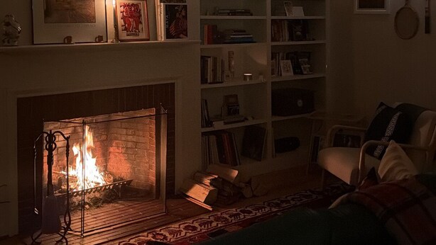 Ein Wohnzimmer mit Kamin, Bücherregal und einer Couch.