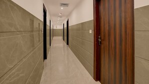 Un pasillo largo y estrecho con paredes de azulejos y una puerta de madera a la derecha.