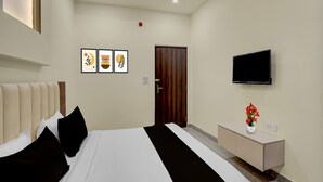 Una habitación de hotel con una cama, televisión, armario y puerta.