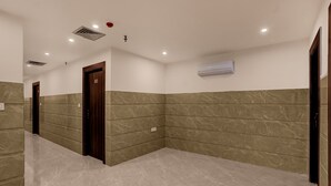 Un pasillo con suelo de mármol, una puerta de madera y un equipo de aire acondicionado en la pared.