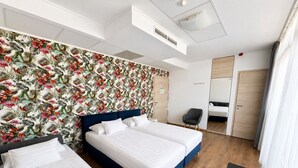 Une chambre d’hôtel avec deux lits, un bureau, une chaise, une armoire et un espace douche.