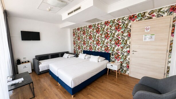 Une chambre d’hôtel avec un lit, un bureau, une chaise, une télévision et une porte avec une pancarte.