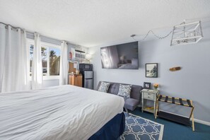 A bedroom with a bed, a desk, a chair, a TV, and a window with curtains. - Eastern Inn Rivercrest Retreat (Conway)