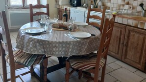 Een eethoek met een ronde tafel, stoelen en een keuken op de achtergrond.