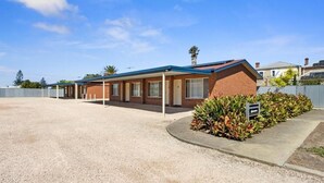 A motel with a gravel driveway, a covered parking area, and a sign indicating a motel. - Edithburgh Seaside Motel (Edithburgh)