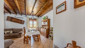 A dining area with a table set for four, wooden chairs, a wooden ceiling, and a white wall with a certificate.