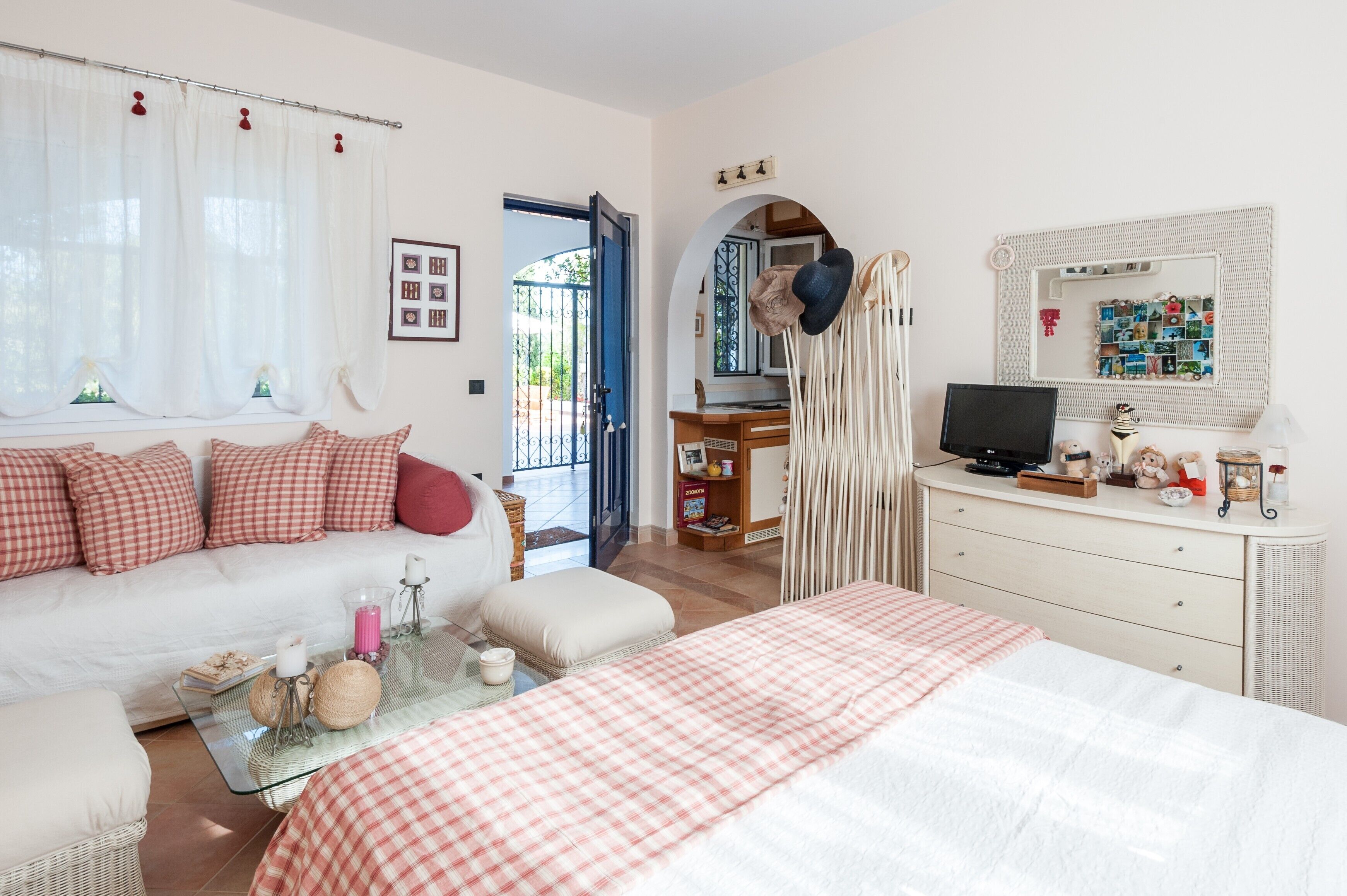 Ein Zimmer mit Bett, Sofa, Schreibtisch, Spiegel und Blick nach draußen.