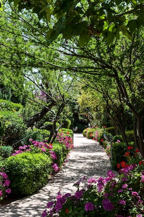 Ein von üppigem Grün und leuchtenden Blumen gesäumter Weg, der durch einen Garten führt.