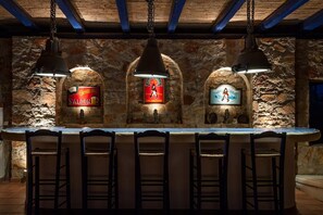 Eine Bar mit Steinwänden, hängenden Lampen und einem Schild für einen Spielsalon.