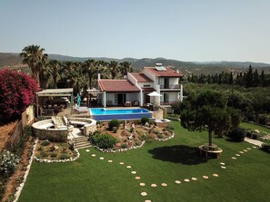 Ein zweigeschossiges Haus mit Swimmingpool, umgeben von einem gepflegten Rasen und Garten.