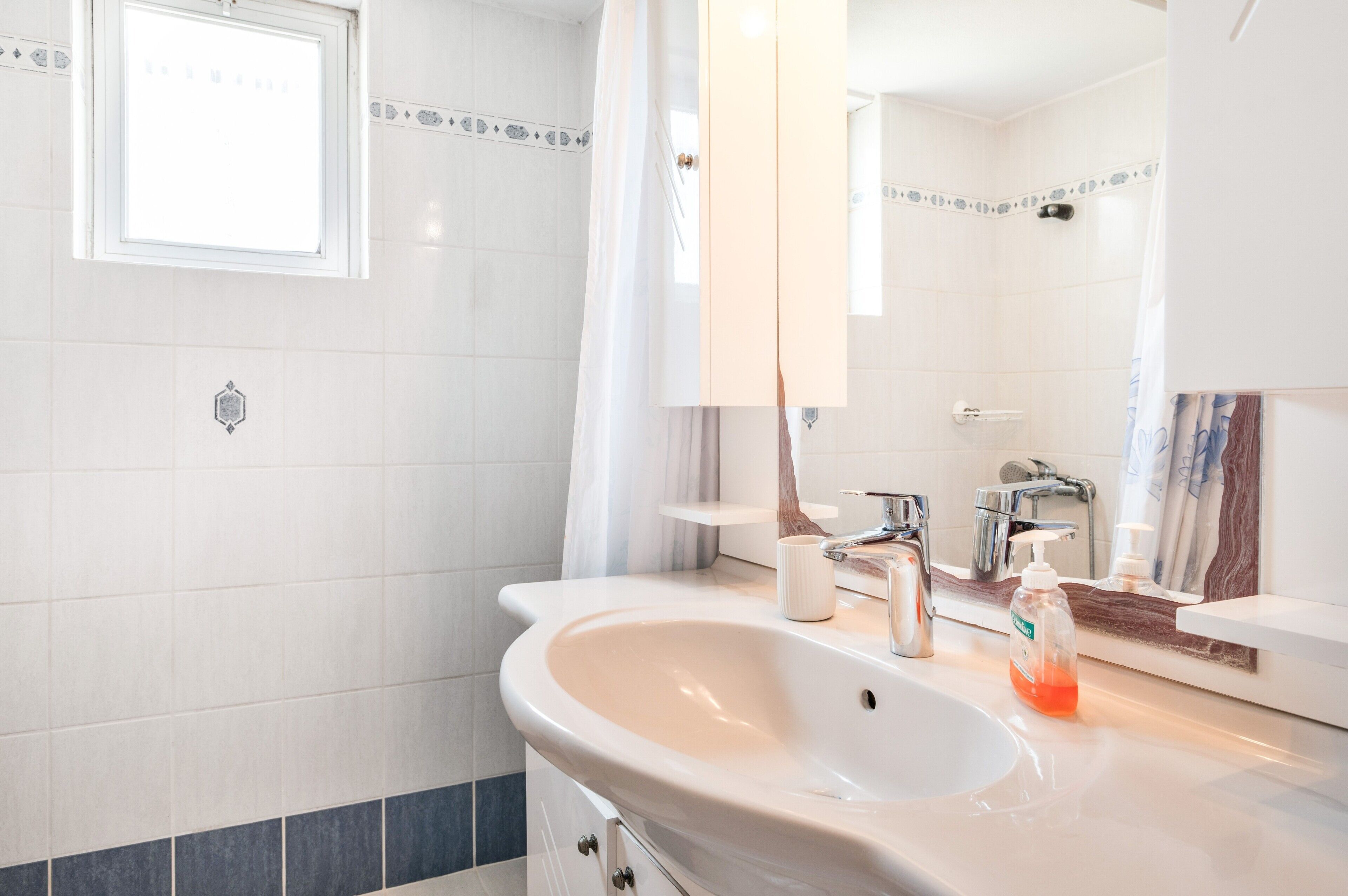 Ein Badezimmer mit Waschbecken, Spiegel und Duschbereich.