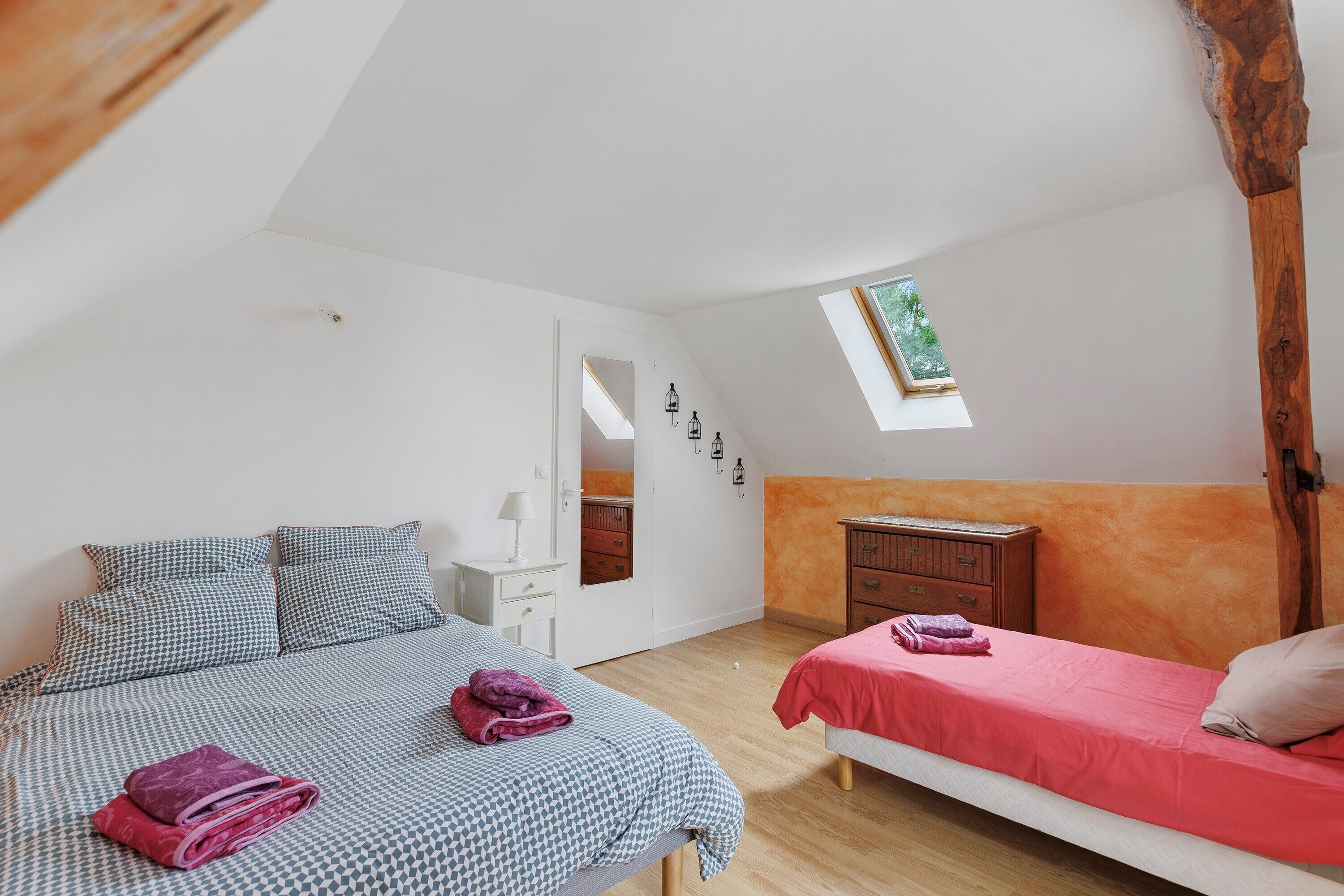 Ein Schlafzimmer mit zwei Betten, Holzboden, Dachfenster, einem Schminktisch und einem Spiegel.