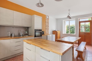 Una cocina moderna con encimera de madera, electrodomésticos de acero inoxidable y pared de ladrillo.