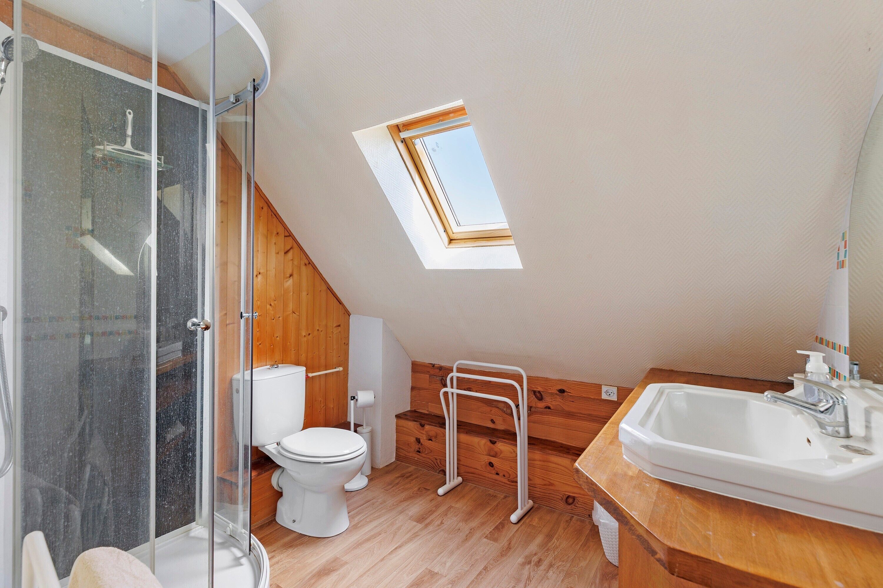 Een kleine, moderne badkamer met dakraam, douche en wastafel.