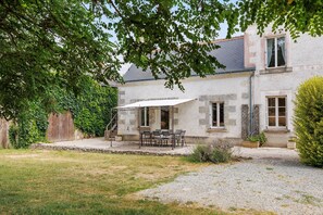 Une maison en pierre dotée d’un patio, d’un espace extérieur aménagé pour s’asseoir et d’une zone couverte.